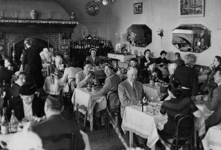 Clients attablés dans le restaurant La Rascasse, anciennement décoré, partageant un dîner de groupe dans une ambiance chaleureuse avec la cheminée allumée.